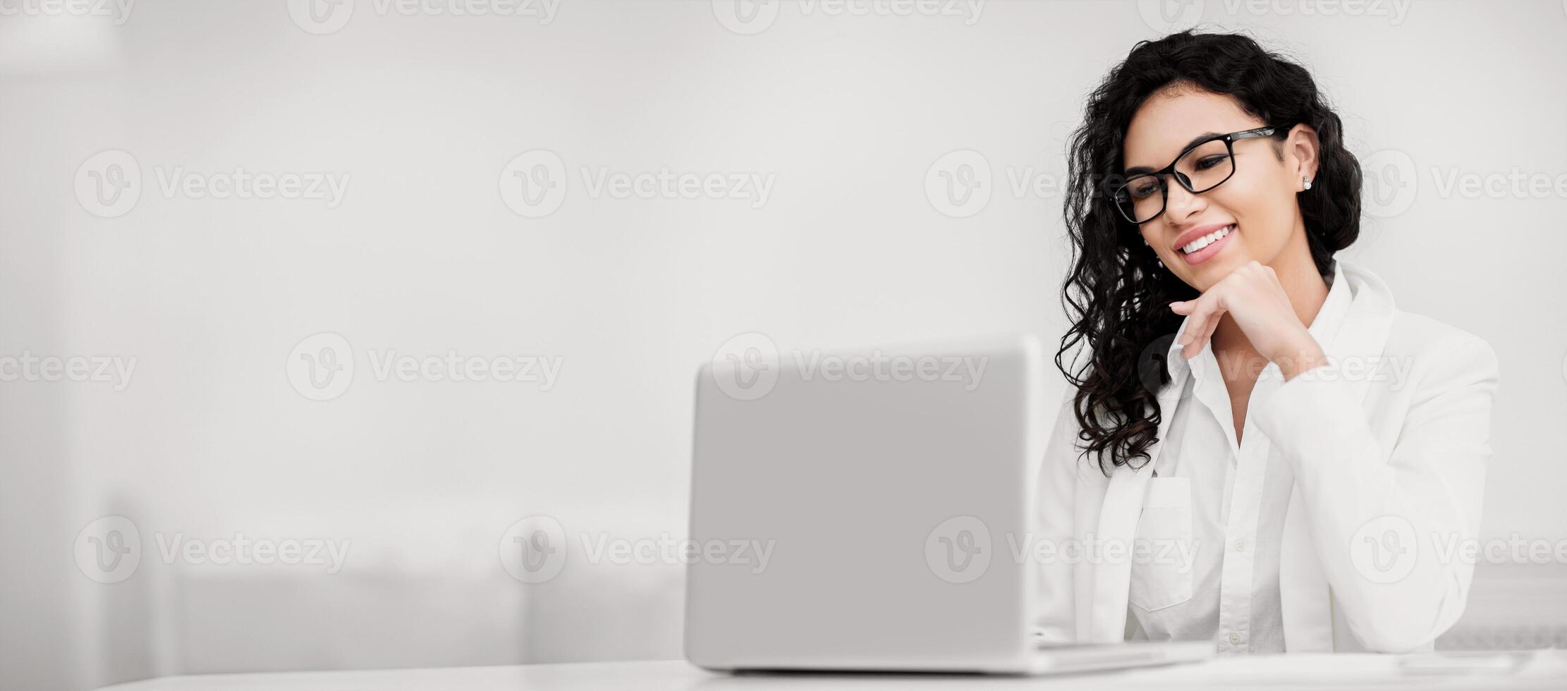 Business Concept. Happy mexican woman using laptop, watching movie, working in modern office, copyspace photo