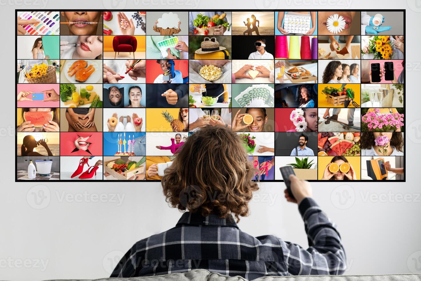 A young person is seated in a living room watching a screen displaying a large grid of colorful images. The images on the screen are diverse, featuring a variety of people, objects, and scenes. photo