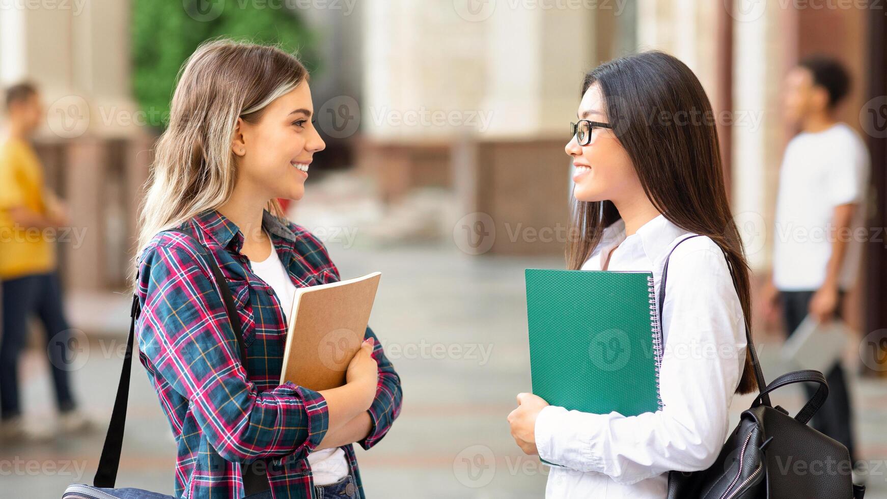Rest between lectures. Girls talking outdoors after class, resting in university campus photo