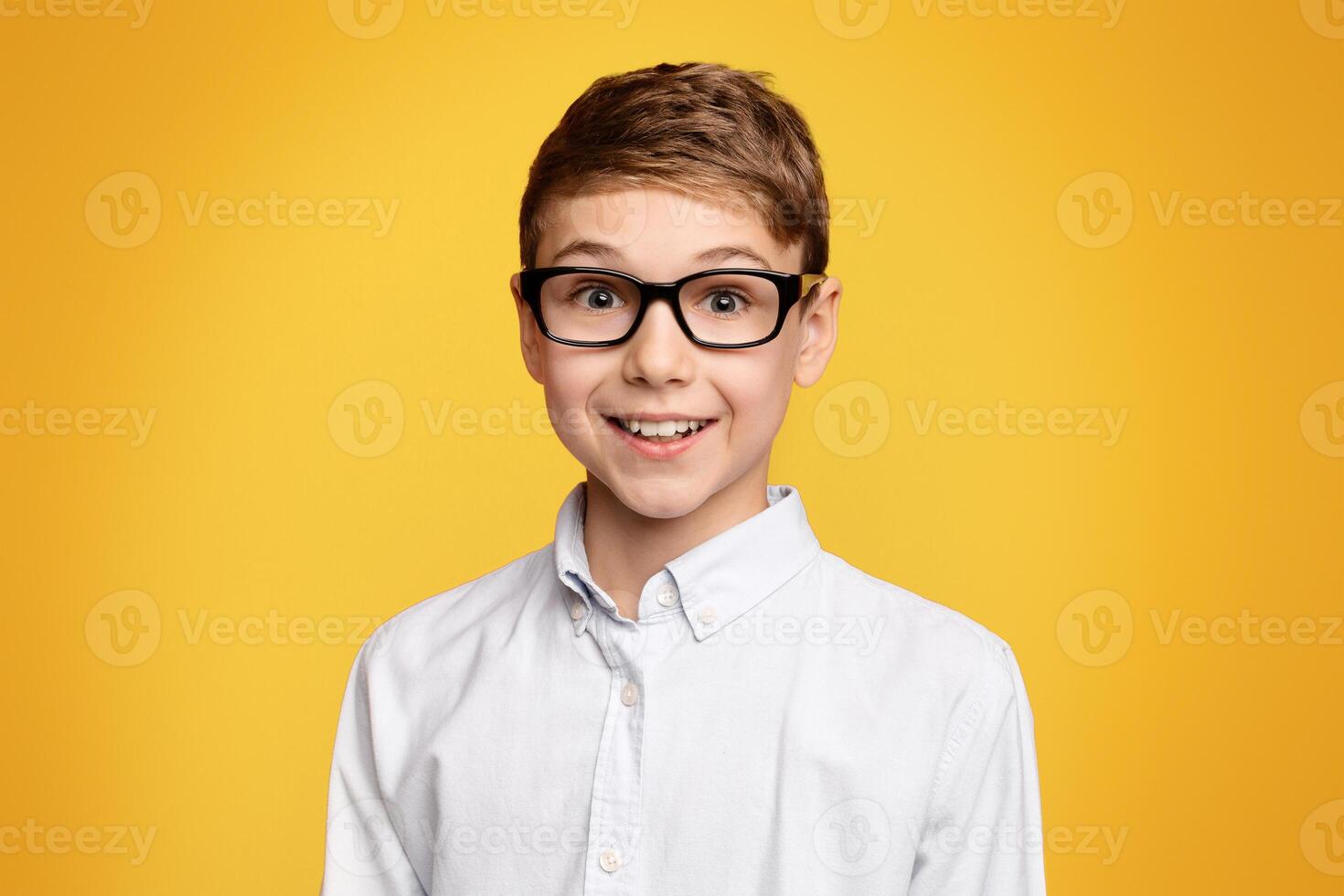 Portrait of cute school boy in glasses, orange panorama background with empty space photo