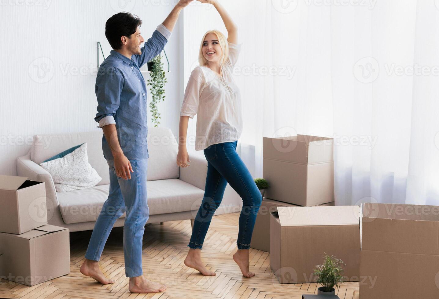 A couple dances in their new home, surrounded by moving boxes, celebrating their new beginning. photo