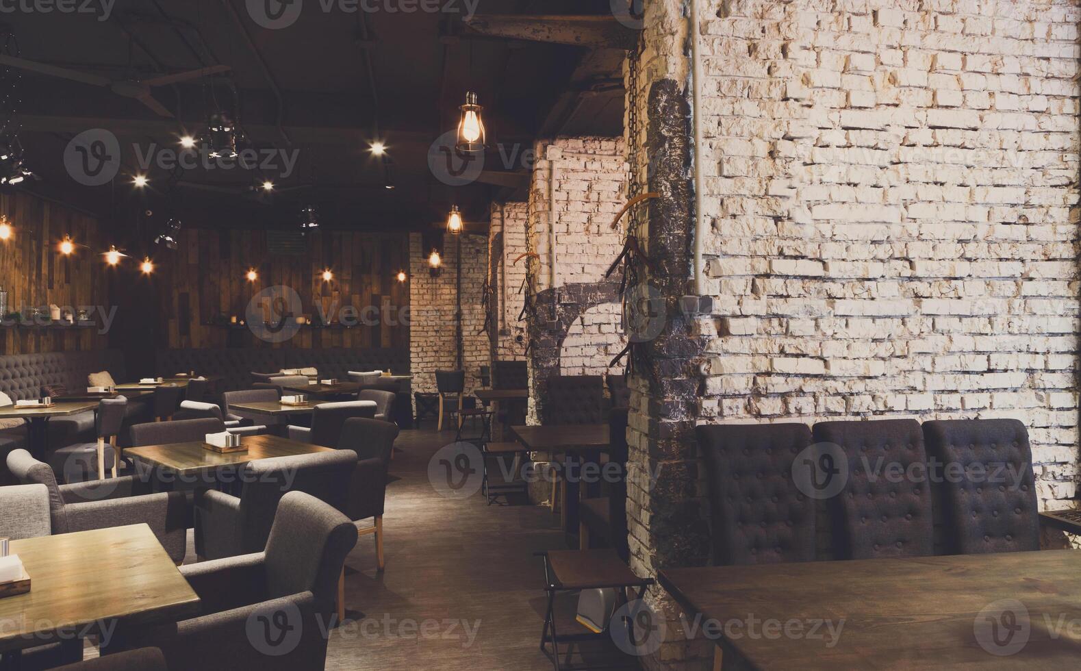Interior of modern restaurant. Contemporary design in loft style, big cozy hall with tables and private cabins with brick wall, copy space photo