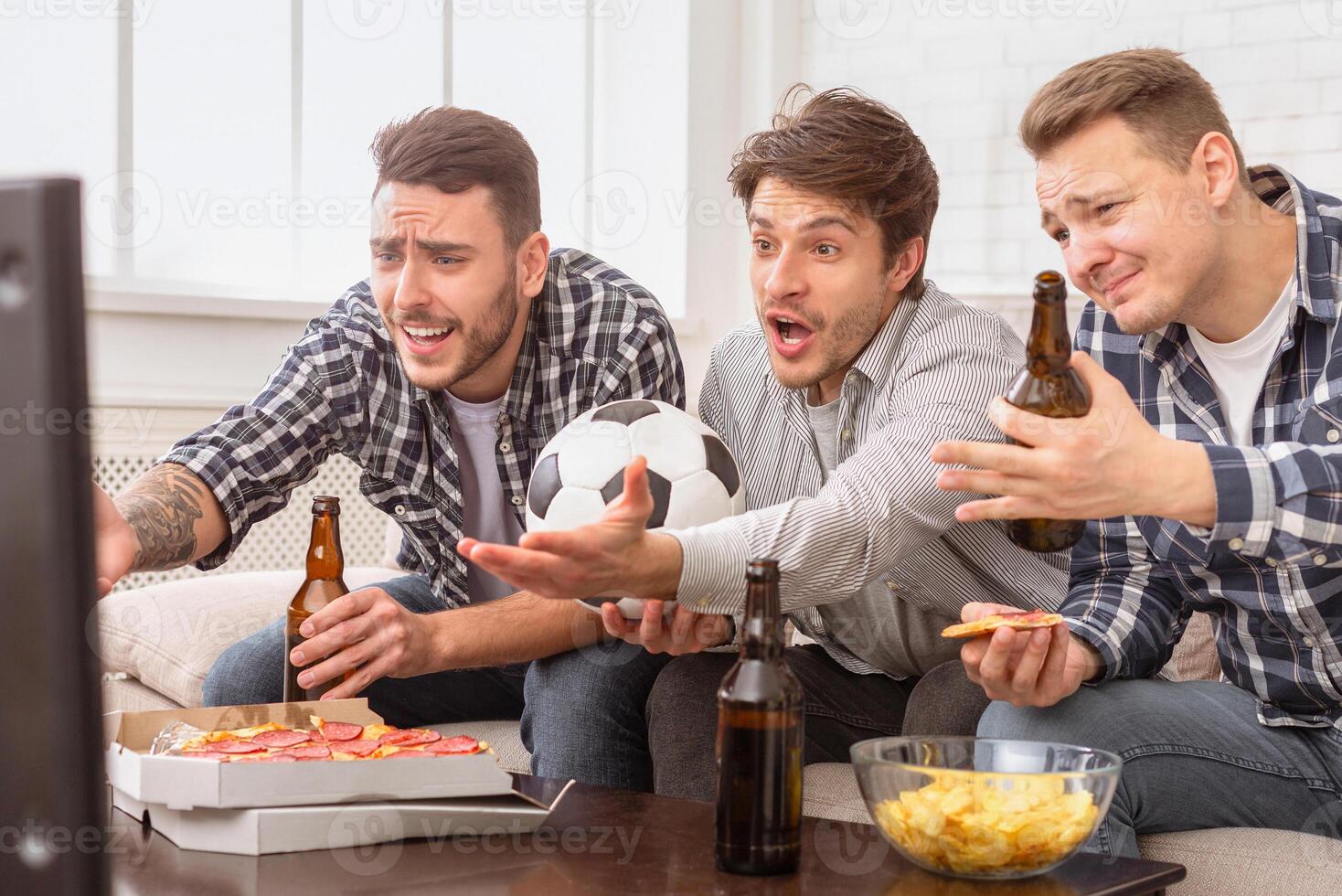 European men engaged in watching a soccer game, express intense emotions that reflect the spirit of friendship among guys photo