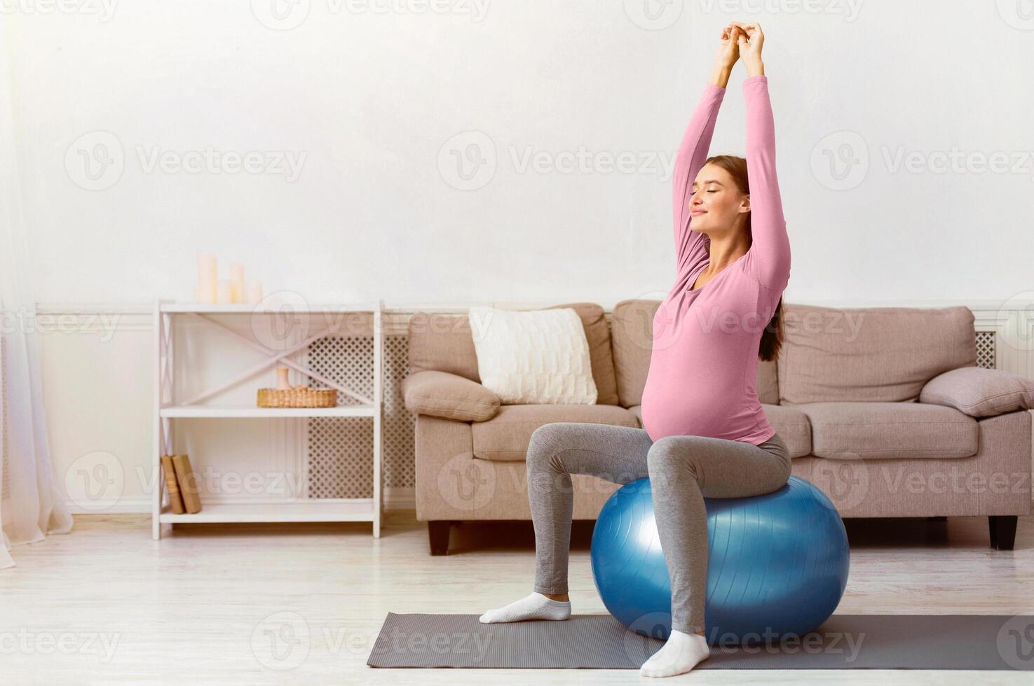 Healthy Lifestyle. Happy pregnant woman exercising on fitball at home. Free space photo