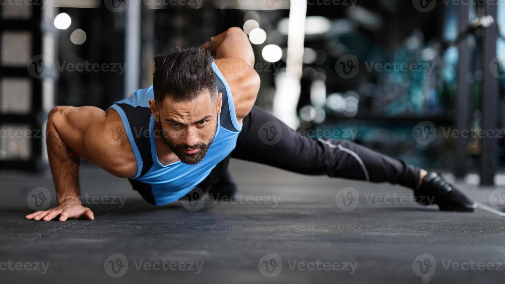 Strength exercise. Muscular man doing push ups on on hands in gym, panorama photo
