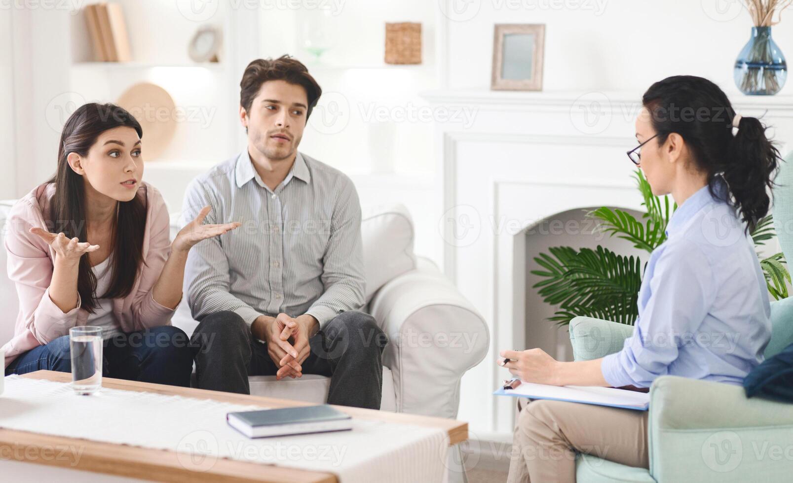 Emotional man and a woman are sitting on a couch, engaged in conversation with a therapist. The therapist is listening attentively and offering guidance in a professional setting. photo