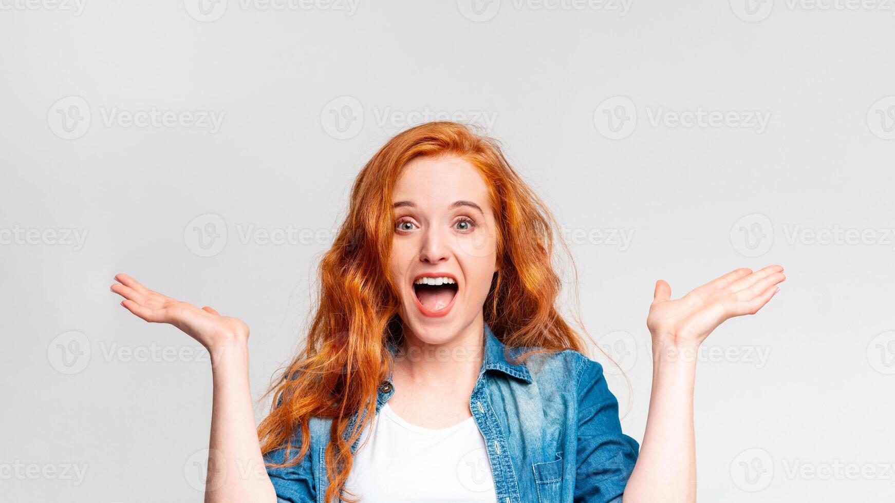A red-haired woman is shown in the photograph, her eyebrows raised and mouth agape in a surprised expression. photo