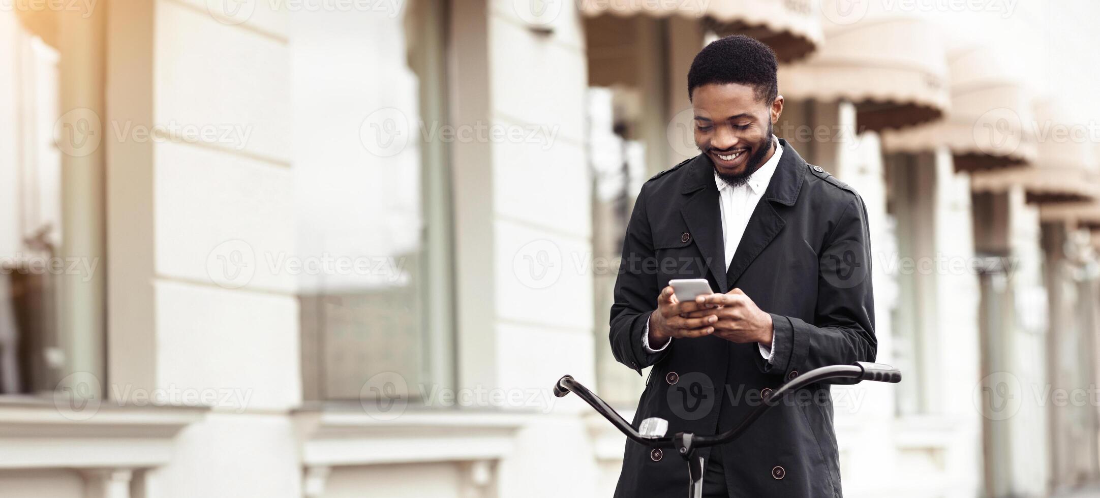 An executive black man is cycling to the office while on the phone. The mood is vibrant and productive, with an urban backdrop highlighting the fusion of business and sustainability. photo