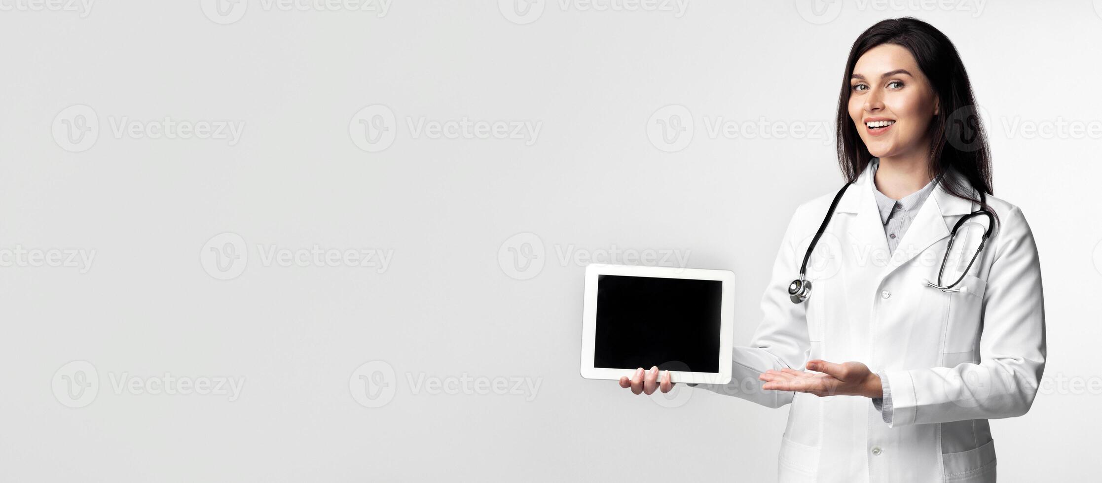 Positive Female Doctor Using Digital Tablet Giving A Presentation Or Medical Lecture On White Studio Background. photo