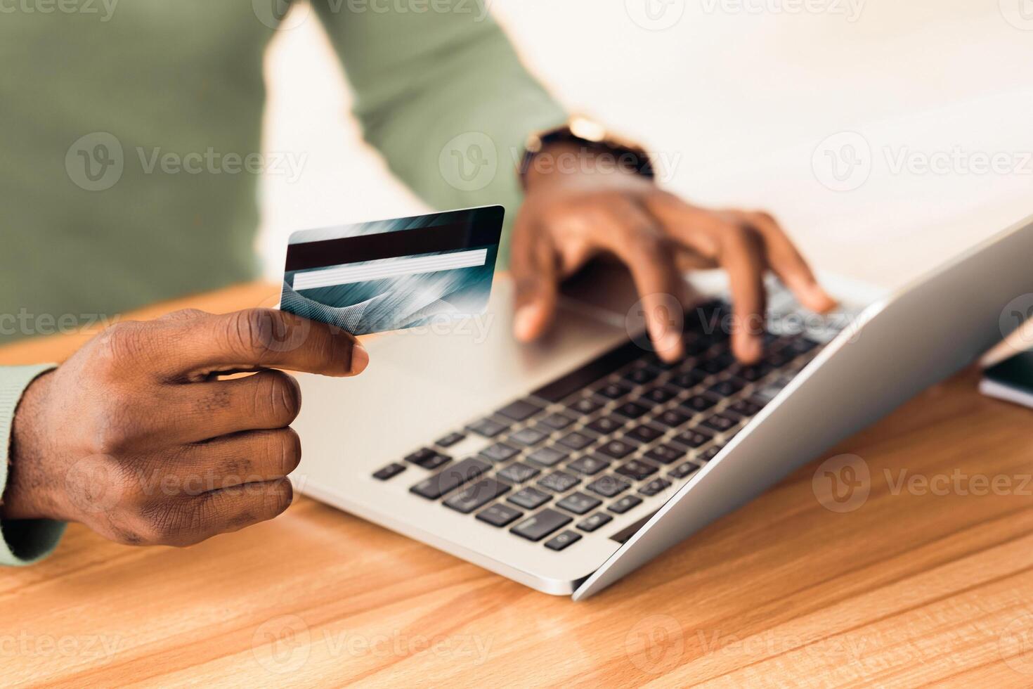 Money Transfer. Unrecognizable african guy holding plastic credit card and using laptop. Copyspace photo