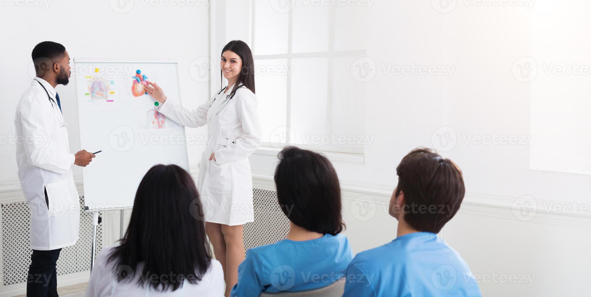 Sharing experience. Practitioners giving lecture to interns at medical seminar in hospital photo