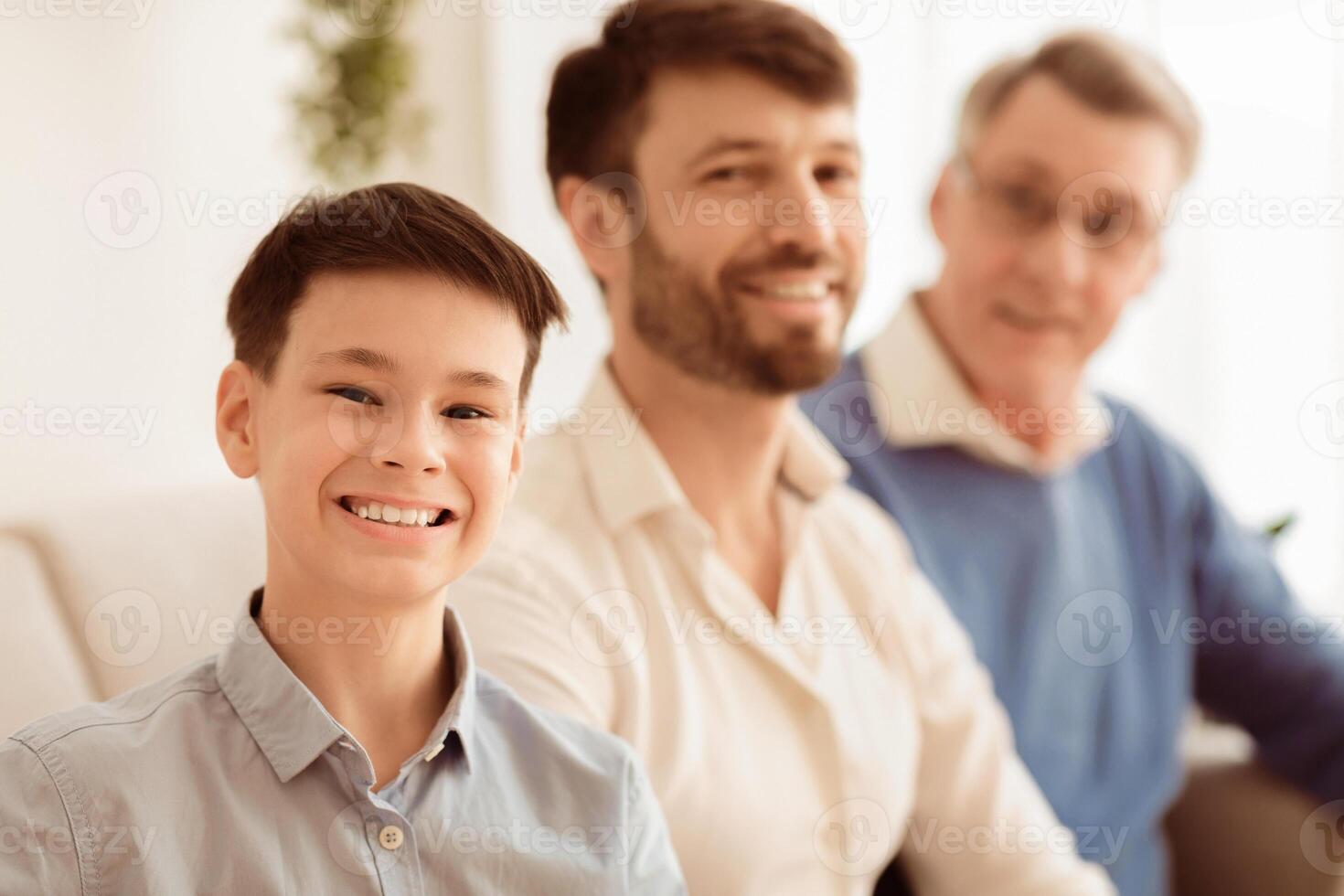 Male Family. Cheerful Boy With Father And Grandfather Smiling At Camera Sitting On Couch At Home. Shallow Depth photo