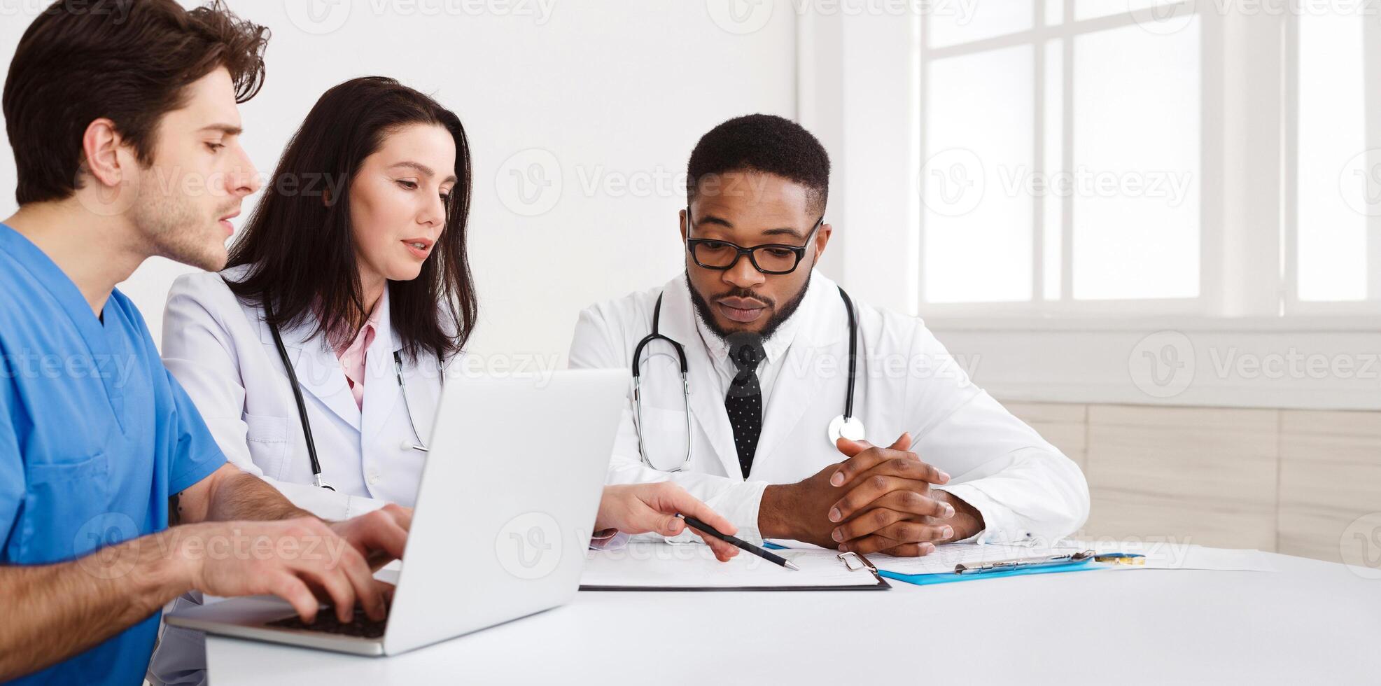 Medical Team Discussing Reports, Using Laptop in Meeting Room photo