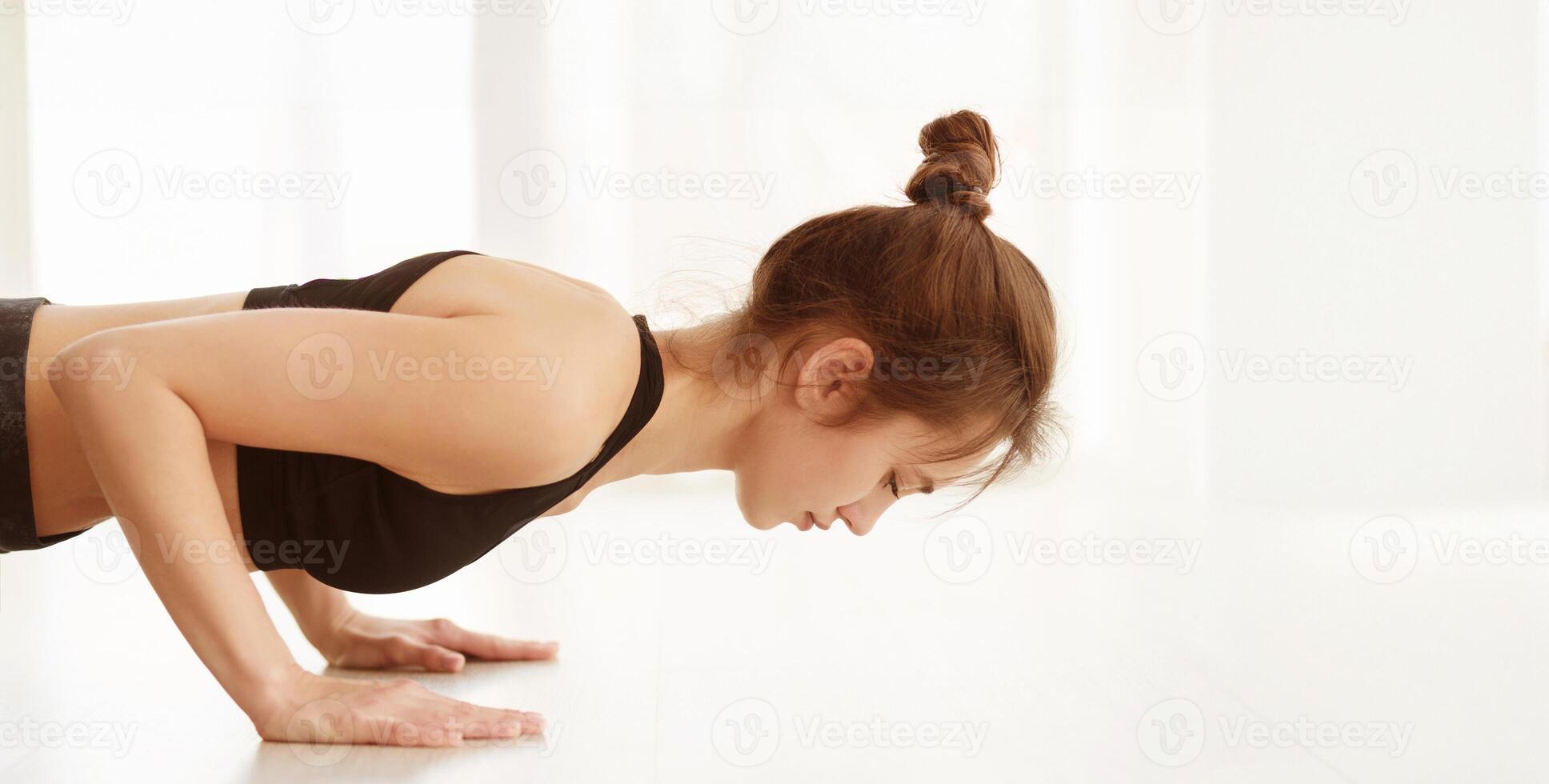 A woman dressed in a black top is engaged in a push-up exercise, demonstrating strength and determination. Her body is extended in a straight line, showcasing proper form and muscle engagement. photo