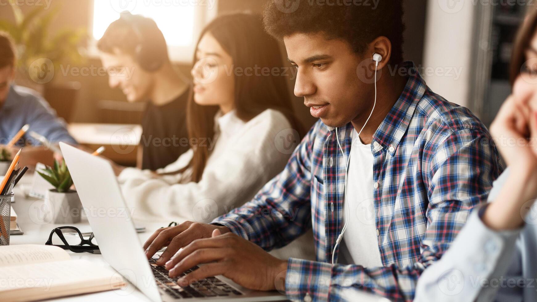 Student learning lessons in school library, making research on laptop and browse internet photo