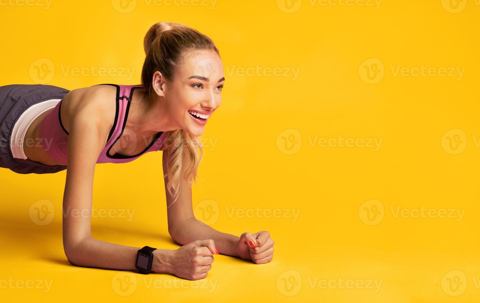 Workout. Fitness Girl Doing Plank Exercise And Smiling Over Pink Studio Background. Free Space photo