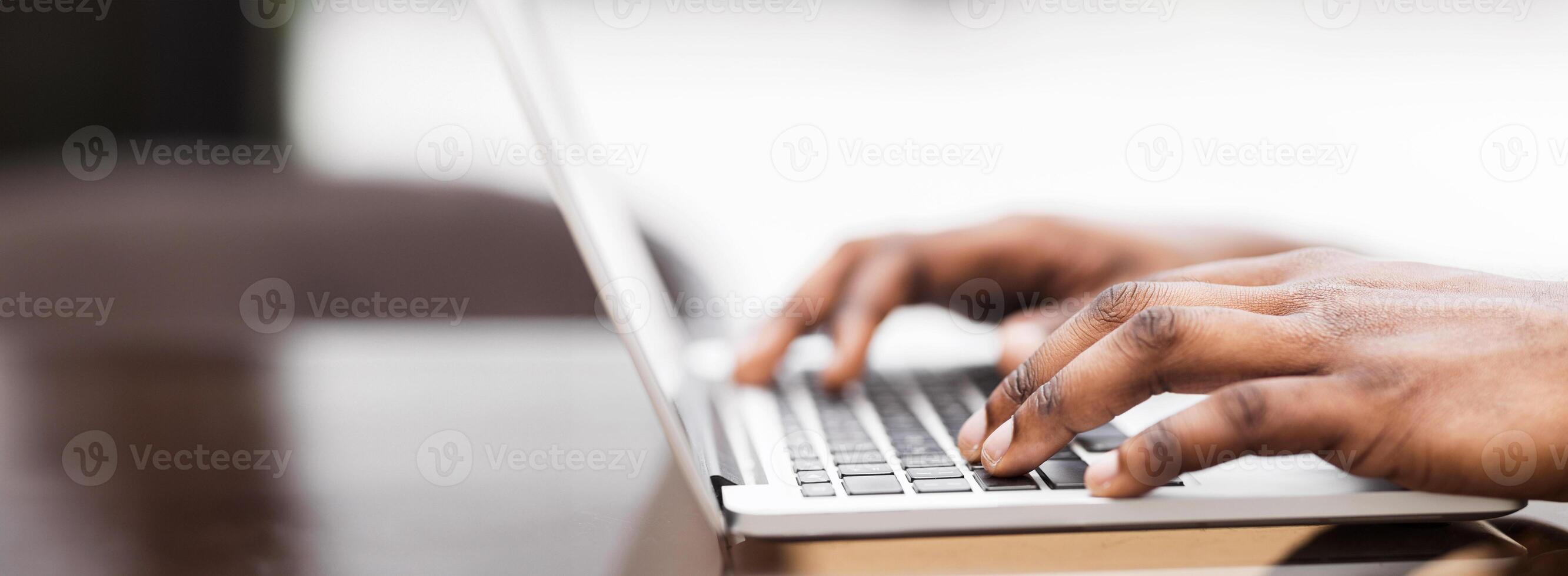 Close-up shot of a persons hands typing on a laptop keyboard. photo