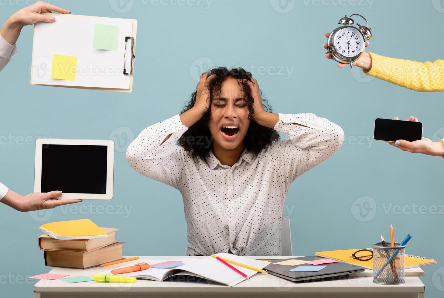 Young African American woman sitting at desk surrounded by hands with alarm clock and gadgets, screaming in despair, feeling exhausted, suffering from burnout. Multitasking, work life balance concept photo