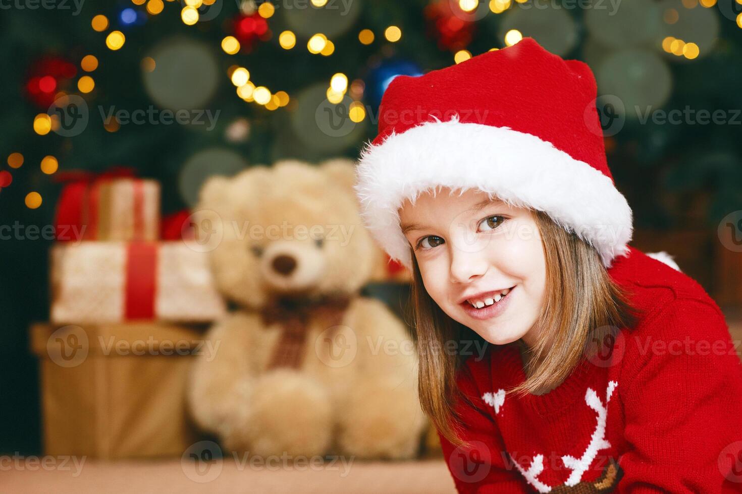 Smiling little girl in red hat laying on floor and writing letter to Santa, copy space photo