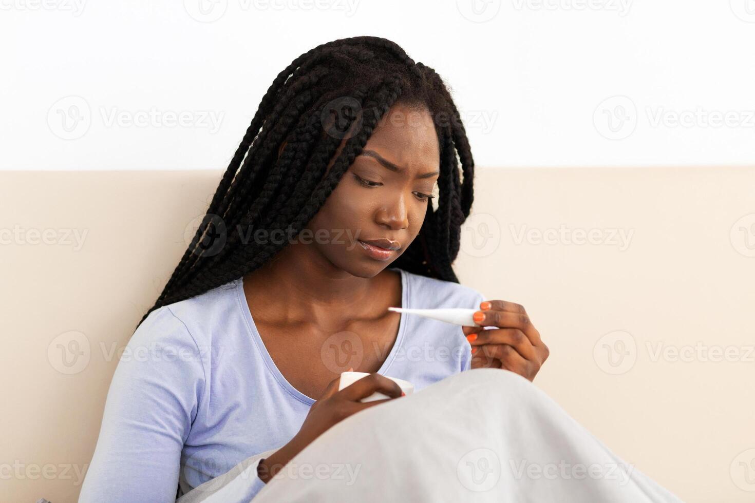 Fever. Sick Black Woman Holding Thermometer Measuring Body Temperature Sitting In Bed At Home. Panorama, Selective Focus photo