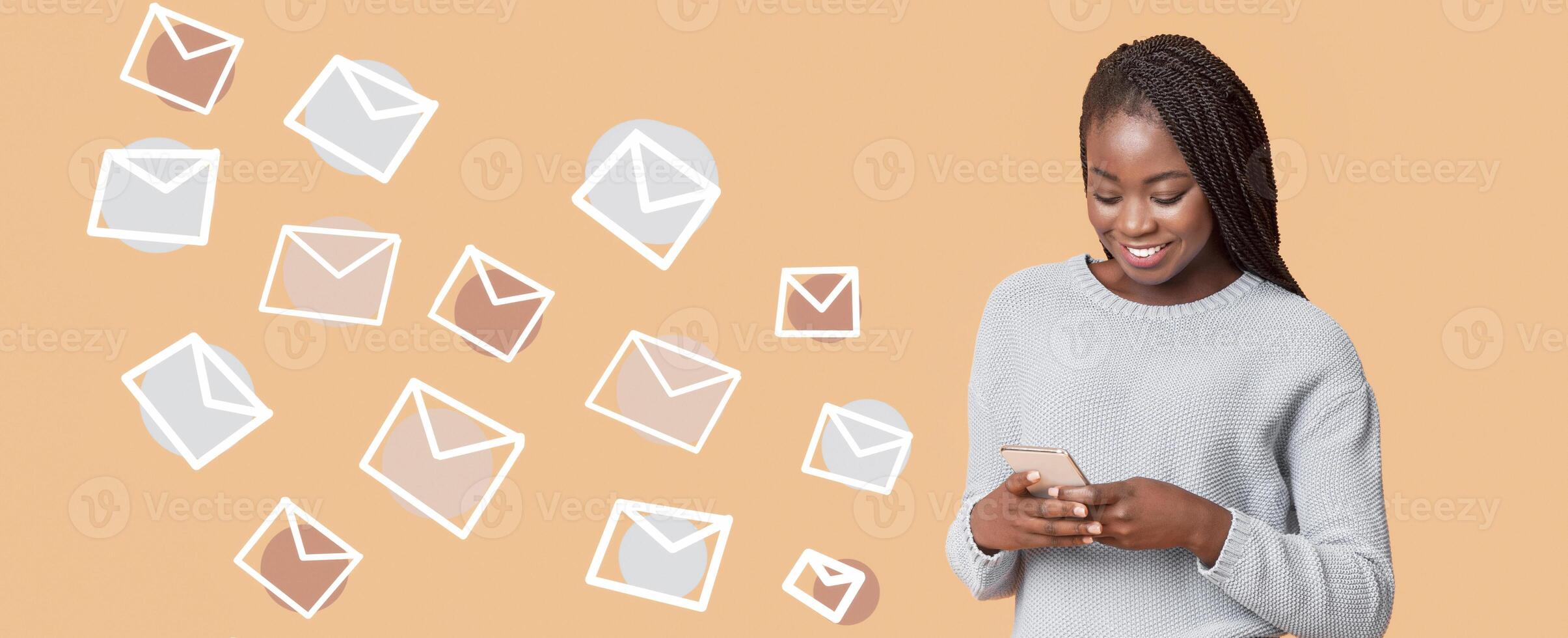 African woman typing text message on smartphone, e-mail inbox envelopes flying from phone, beige background, panorama photo