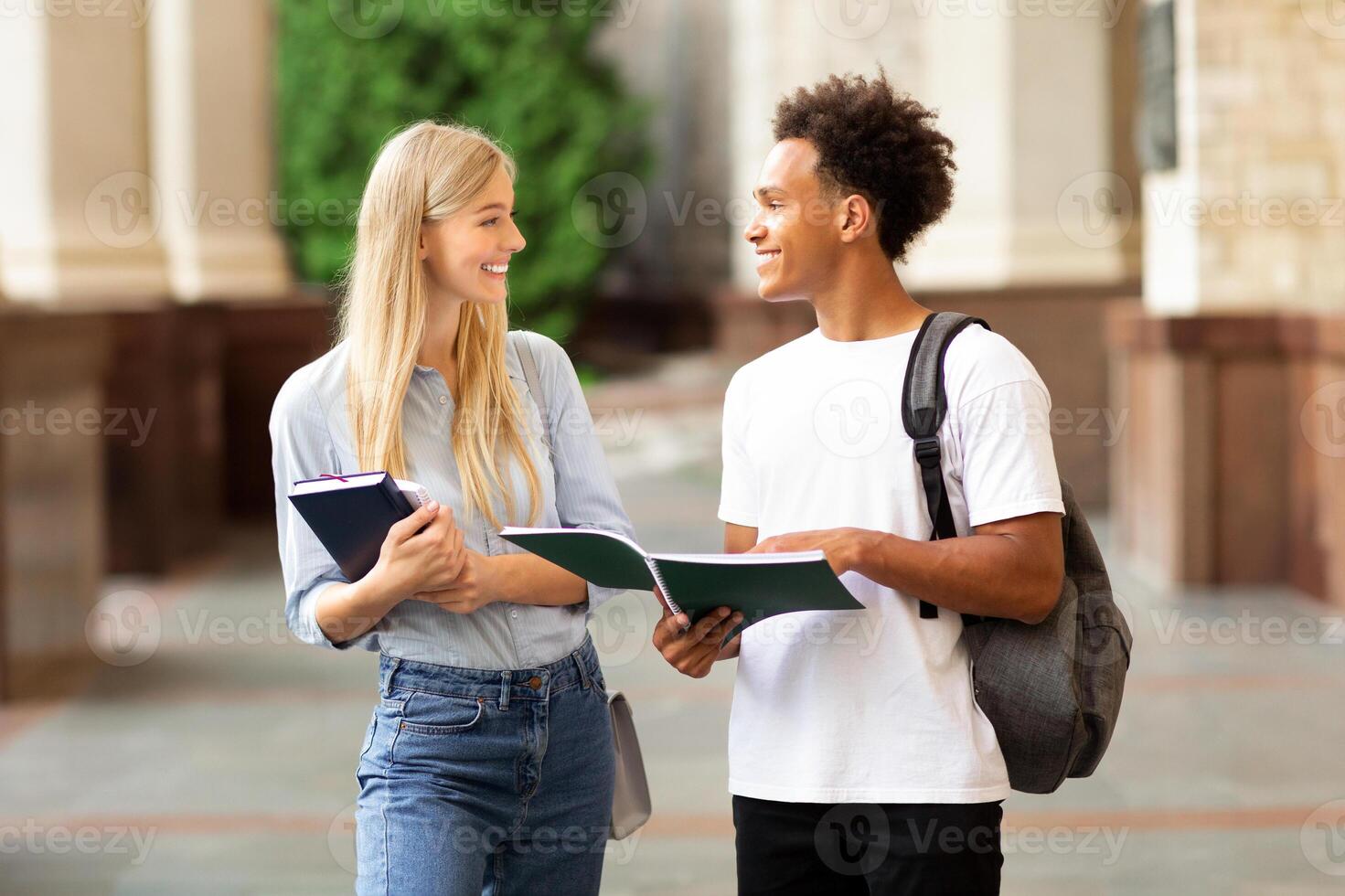 Students chatting, walking in university campus outdoors between classes, copy space photo