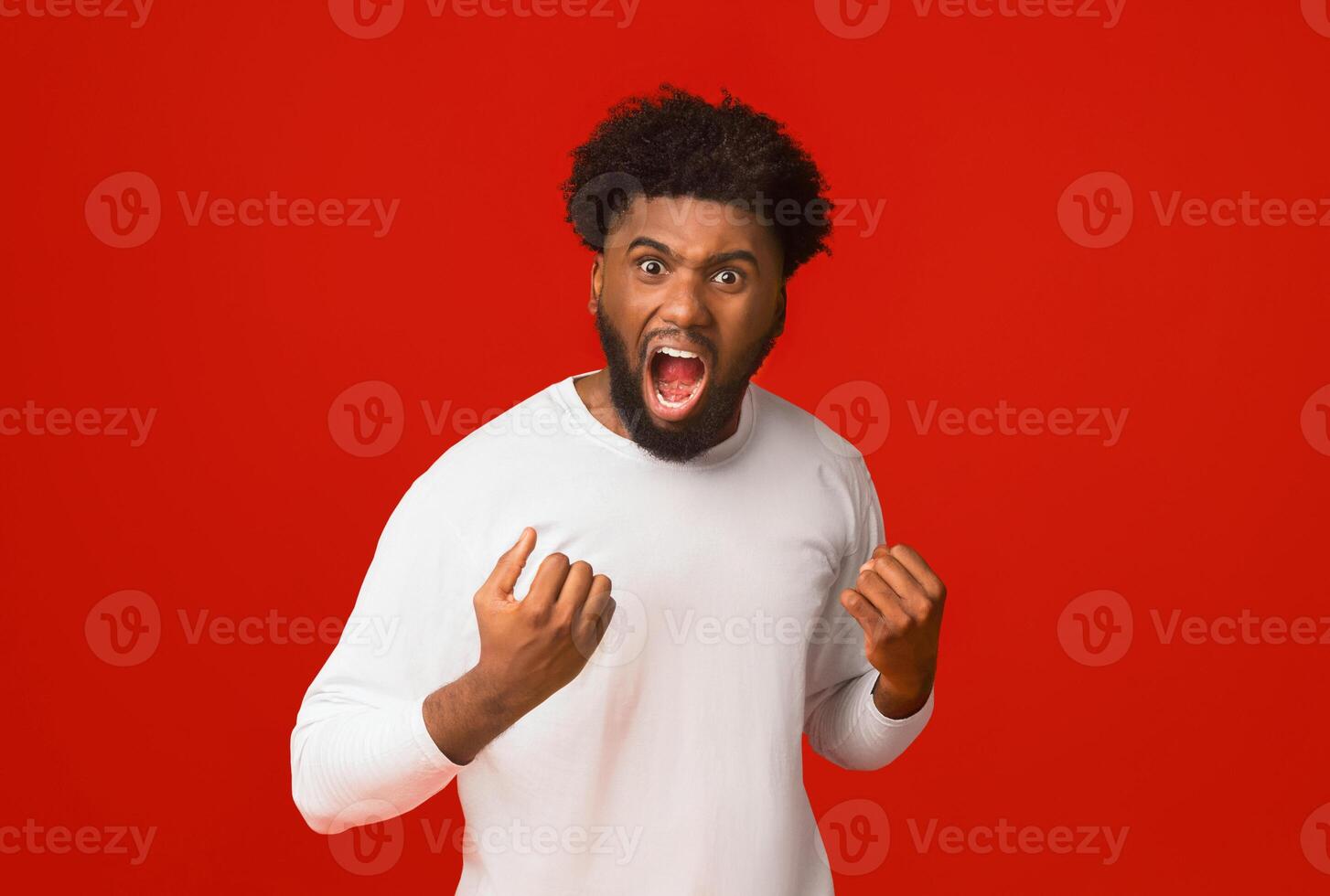 Furious black man shouting over orange background, ready for fight photo