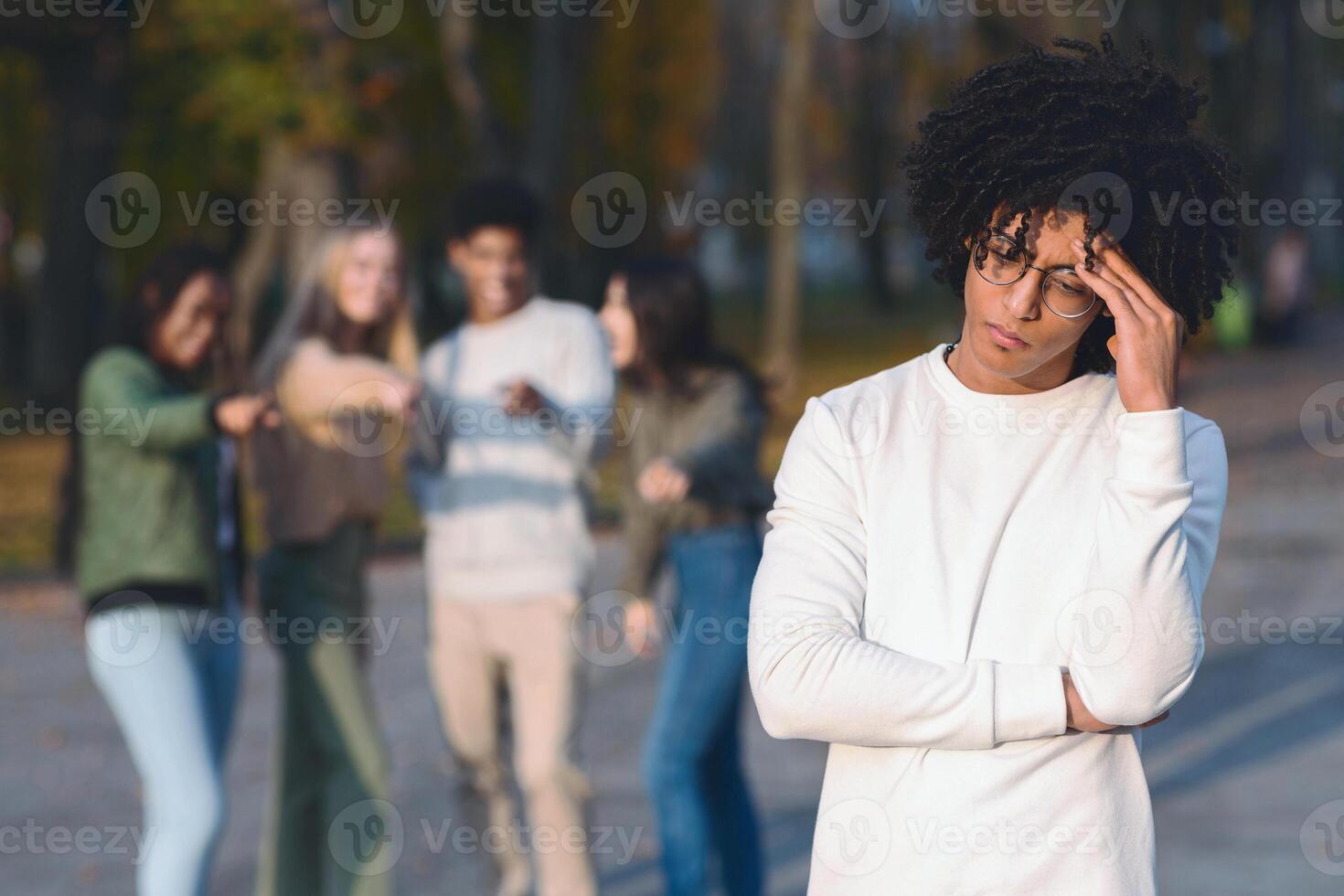 Multiracial group of teenagers pointing at frustrated black guy, spending time in park photo