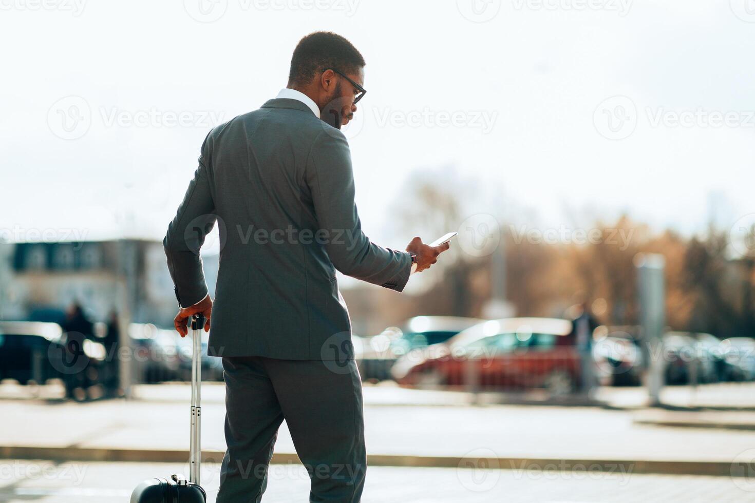 Businessman Ordering Taxi, Using Mobile Phone App, Arriving At Airport photo