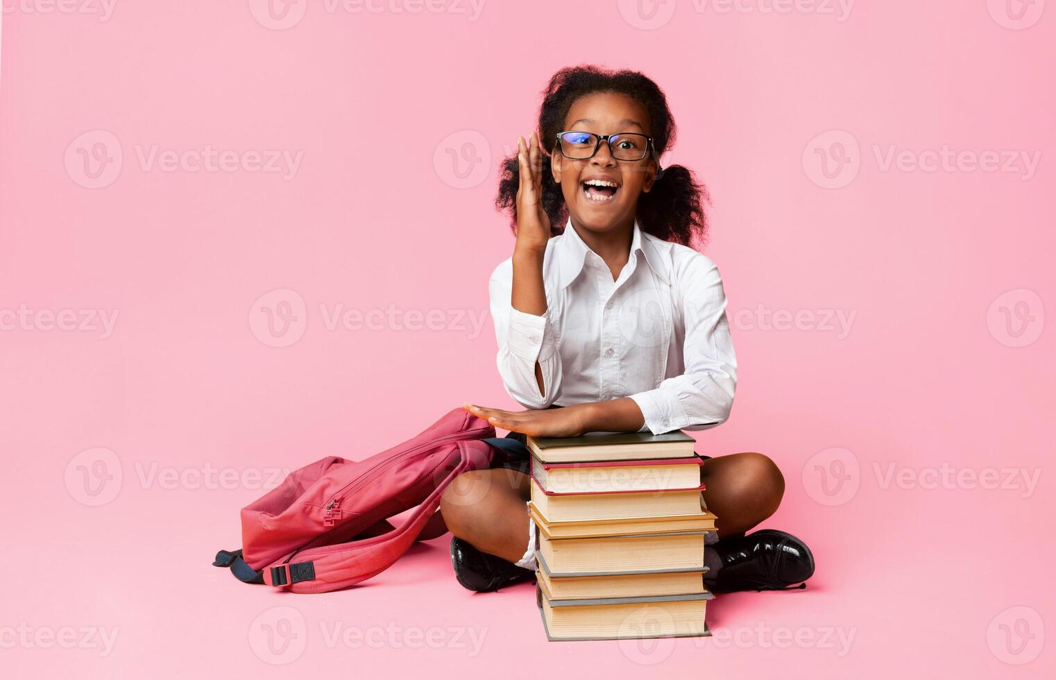 Back To School. Nerdy Schoolgirl Raising Hand During Class Sitting At Books Over Yellow Studio Background. Free Space photo