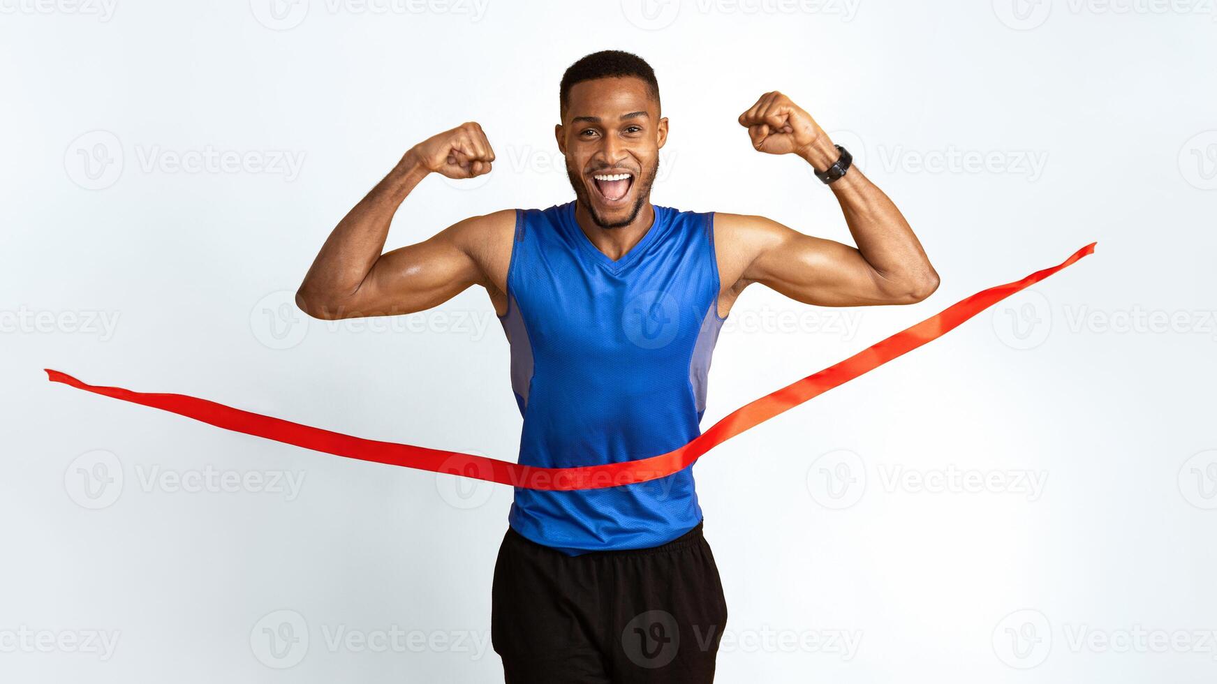 Male Athlete. Happy afro guy crossing the finish line, making winner gesture, breaking red tape, yellow studio wall photo