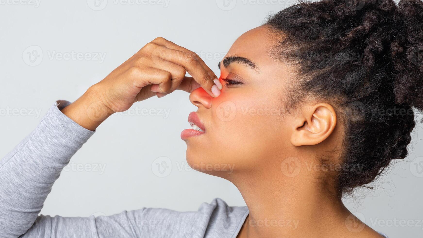 Indignant young black woman touching nose bridge, highlighted red zone, side view photo