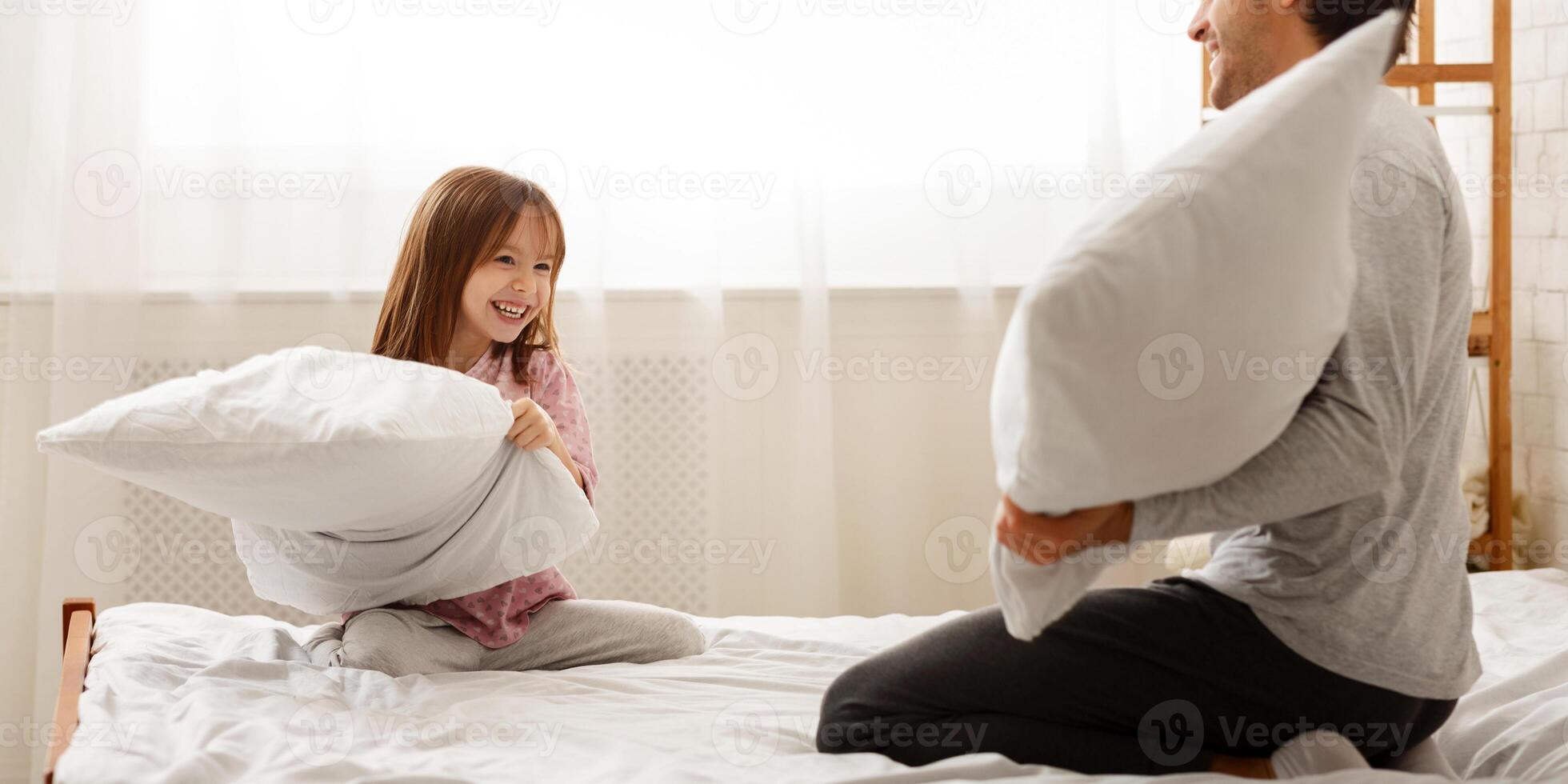 Family daughter and dad having pillow fight together in bedroom, empty space photo