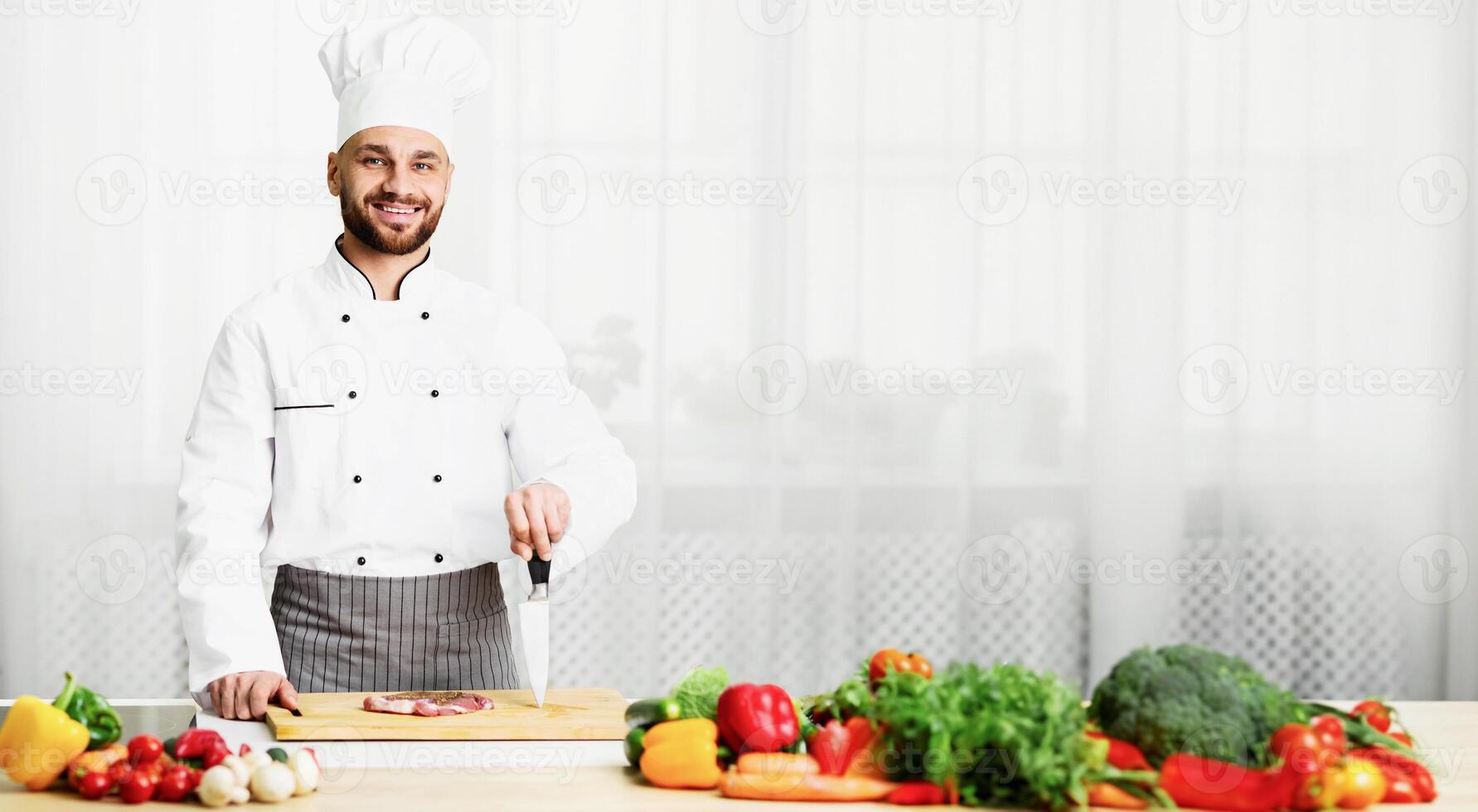 Chef Man Cooking Fresh Meat Steak Posing Holding Knife Smiling At Camera Standing In Kitchen Indoor. Selective Focus photo