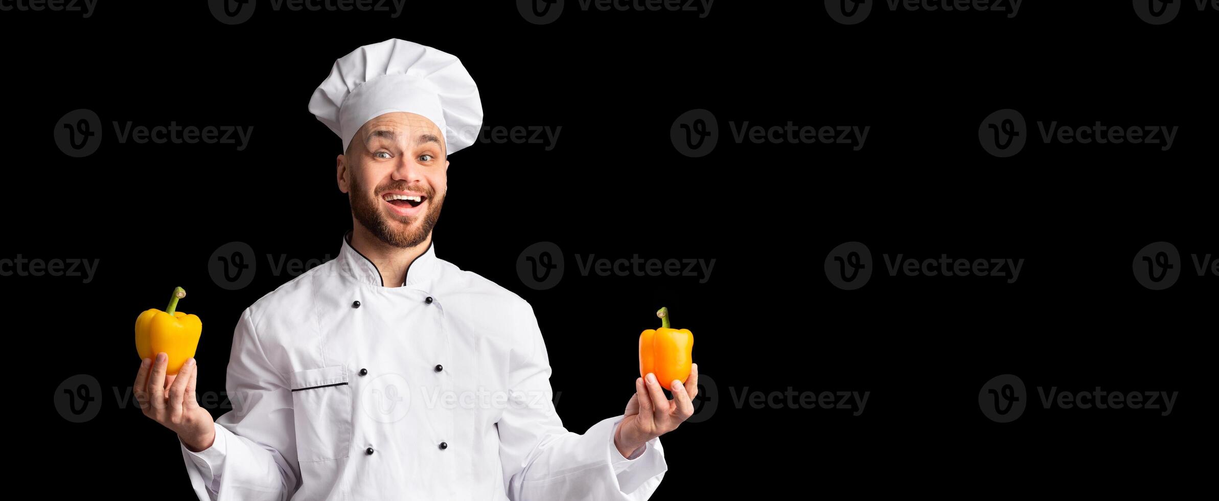 Vegetarian Menu. Happy Chef Man Holding Two Yellow Sweet Peppers Smiling To Camera Posing Over Black Studio Background. Panorama photo