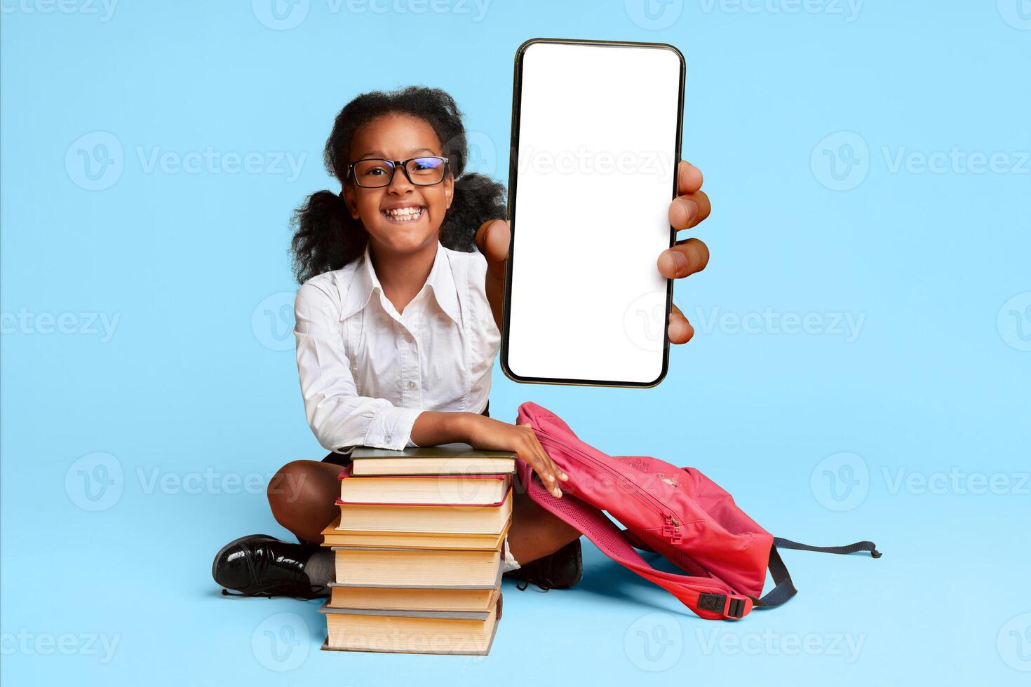 I Like School. Afro Schoolgirl Gesturing Thumbs-Up Sitting At Book Stack In Studio Over Yellow Background. Empty Space photo