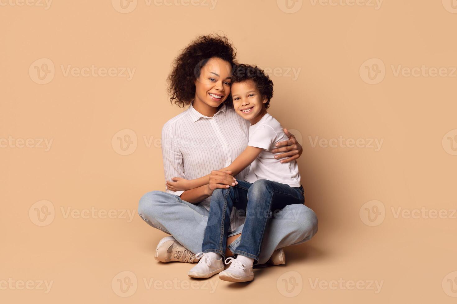 African American woman and a child are seated on the ground, quietly engaging in conversation. The child appears attentive, while the woman gestures with her hands as she speaks. photo