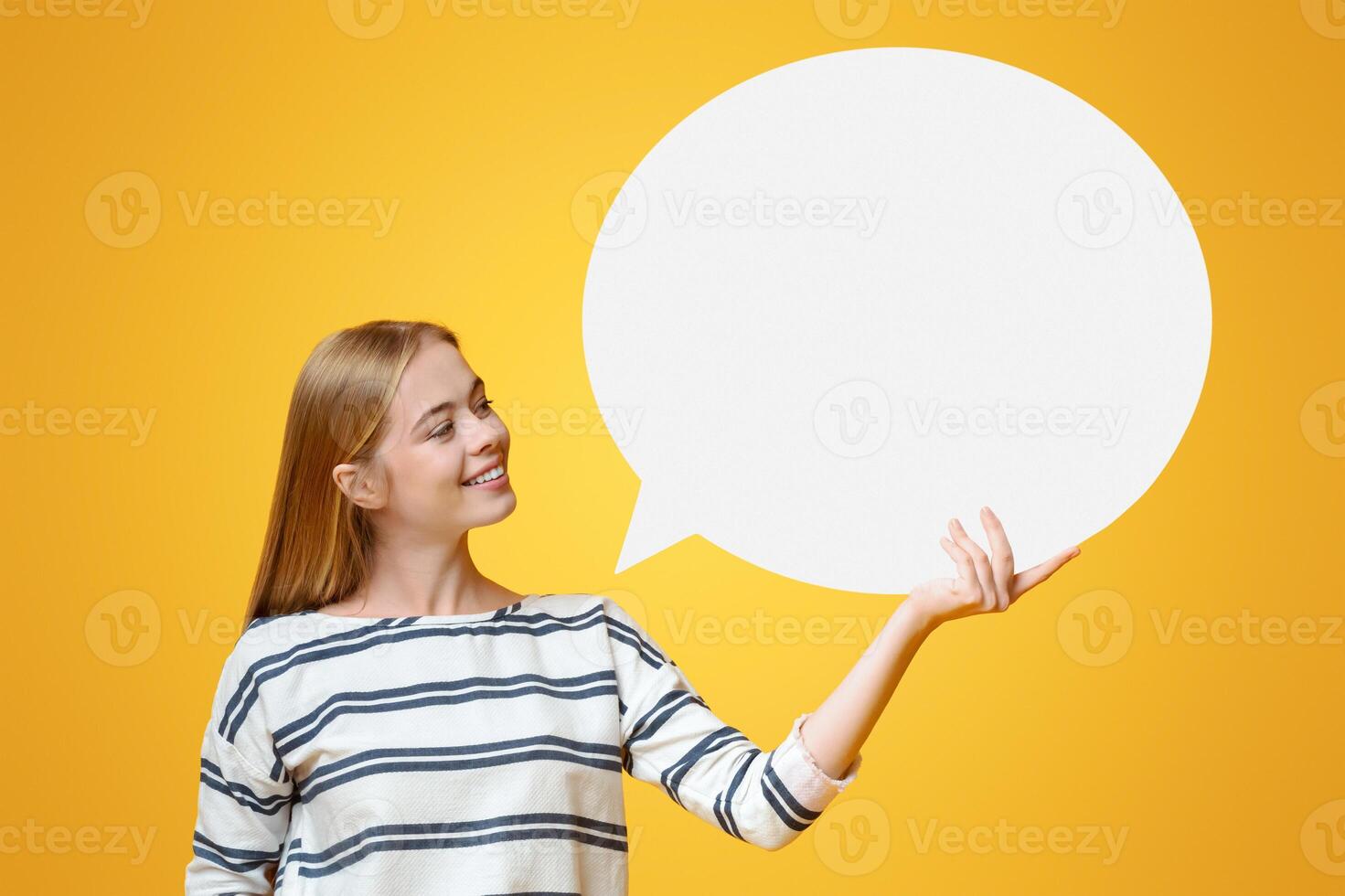 Blank speech bubble in hands of beautiful young girl over yellow background, copy space photo