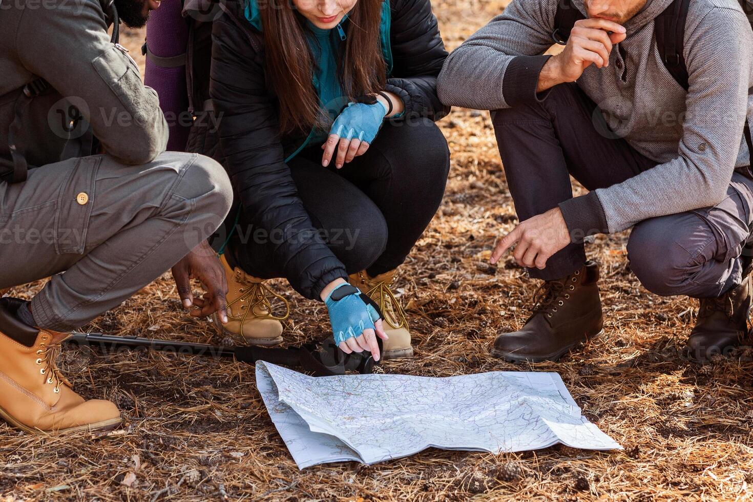 Confused group of multiethnic hikers looking at map, lost in forest photo