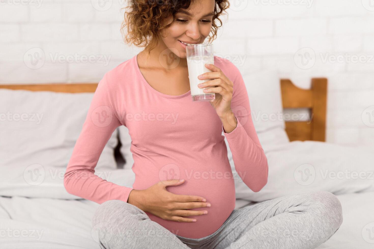 Healthy breakfast for pregnant woman, enjoying milk in the morning, sitting on bed photo