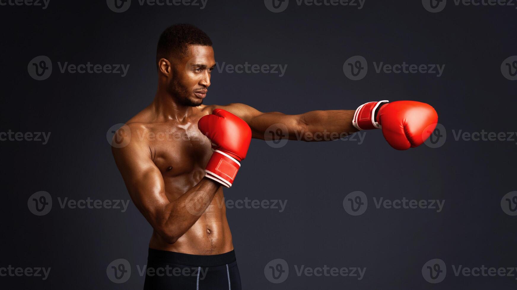 Strength And Motivation. Young attractive black man boxer is ready to deal on ring isolated over black wall, copyspace photo