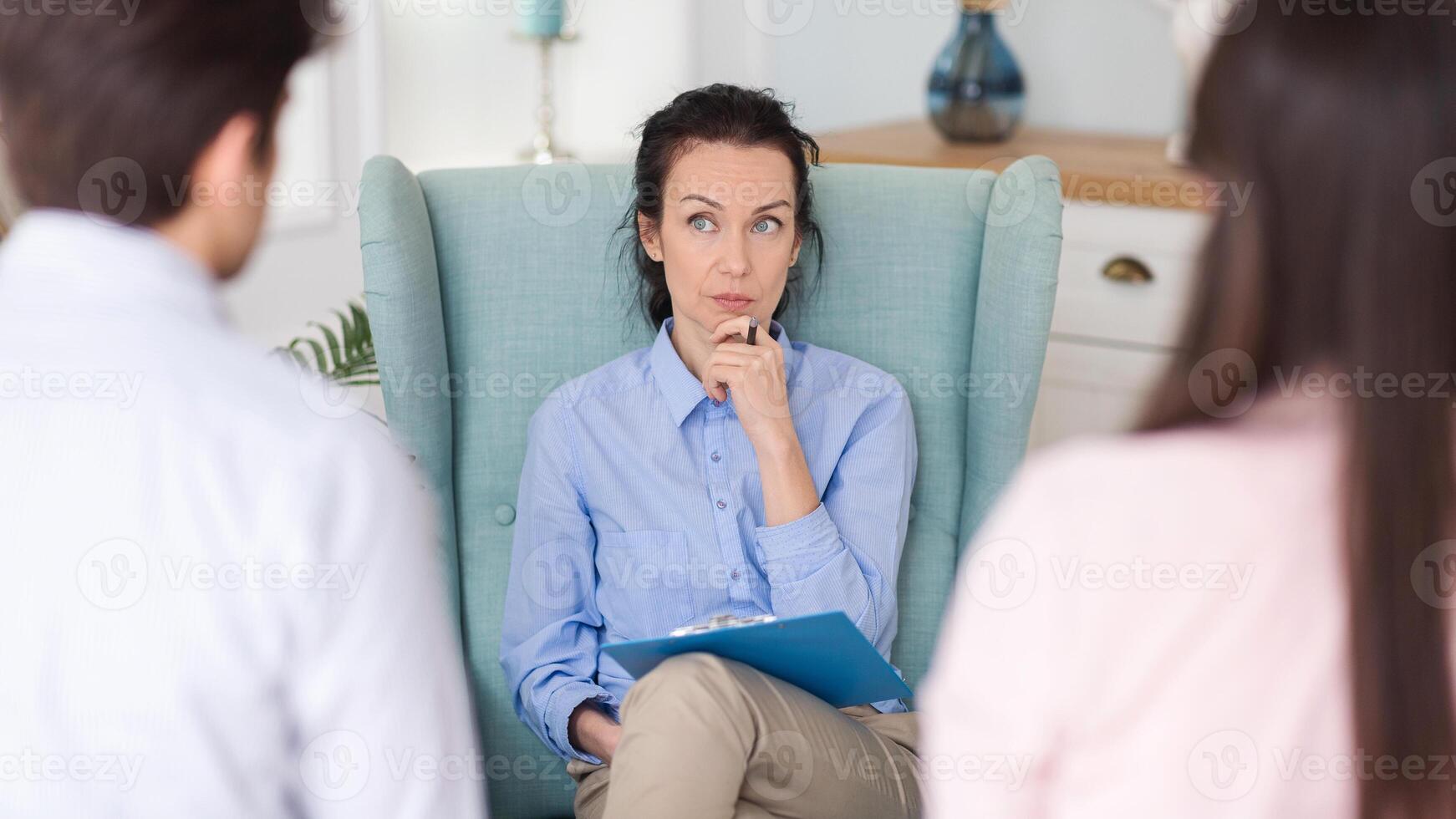 In a comfortable therapy environment, a young couple discusses their emotional challenges with a lady psychologist, working towards healing and understanding. photo