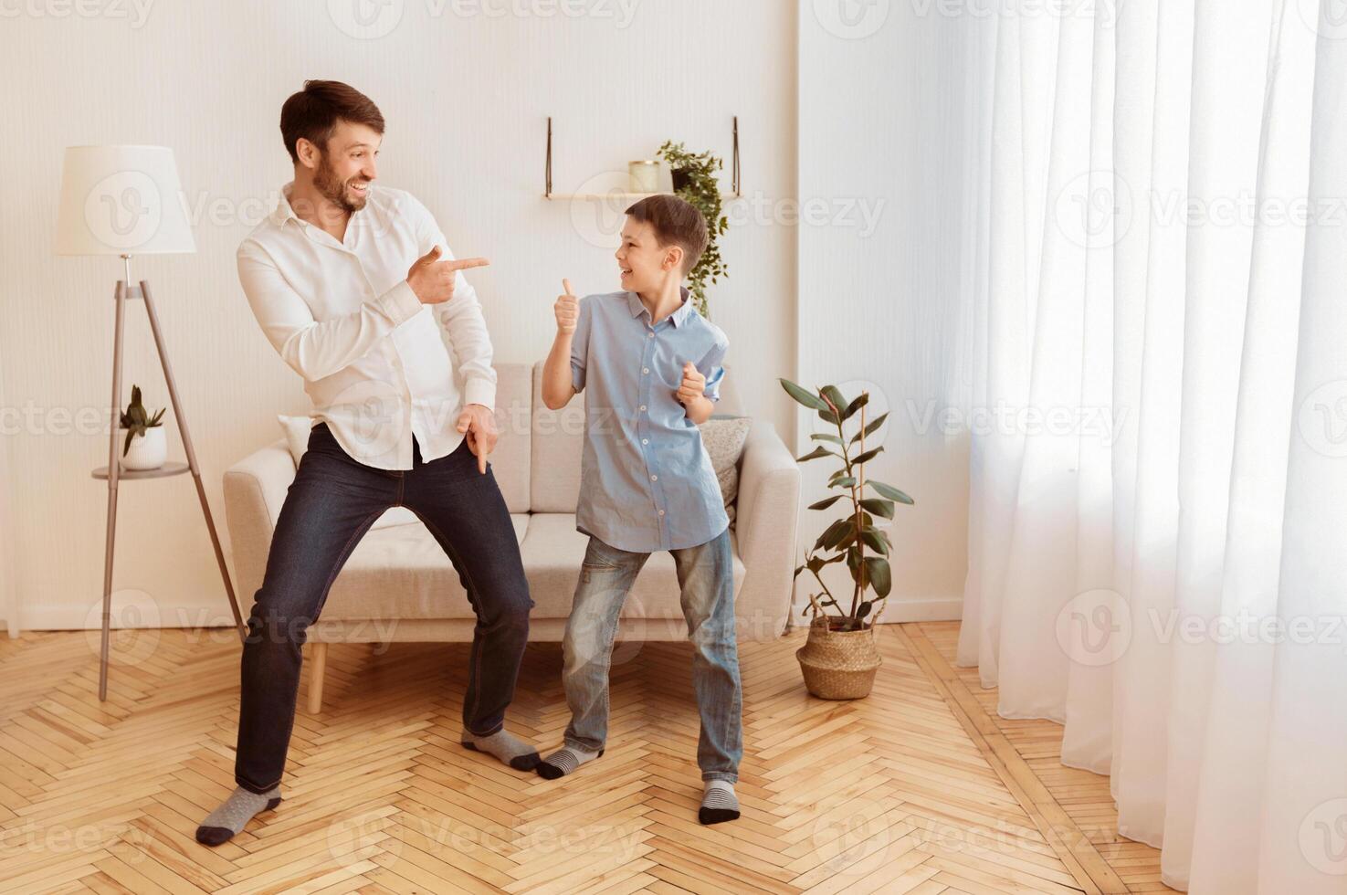 Father And Son. Happy Man And His Kid Having Fun Dancing And Fooling Around At Home. Free Space For Text photo