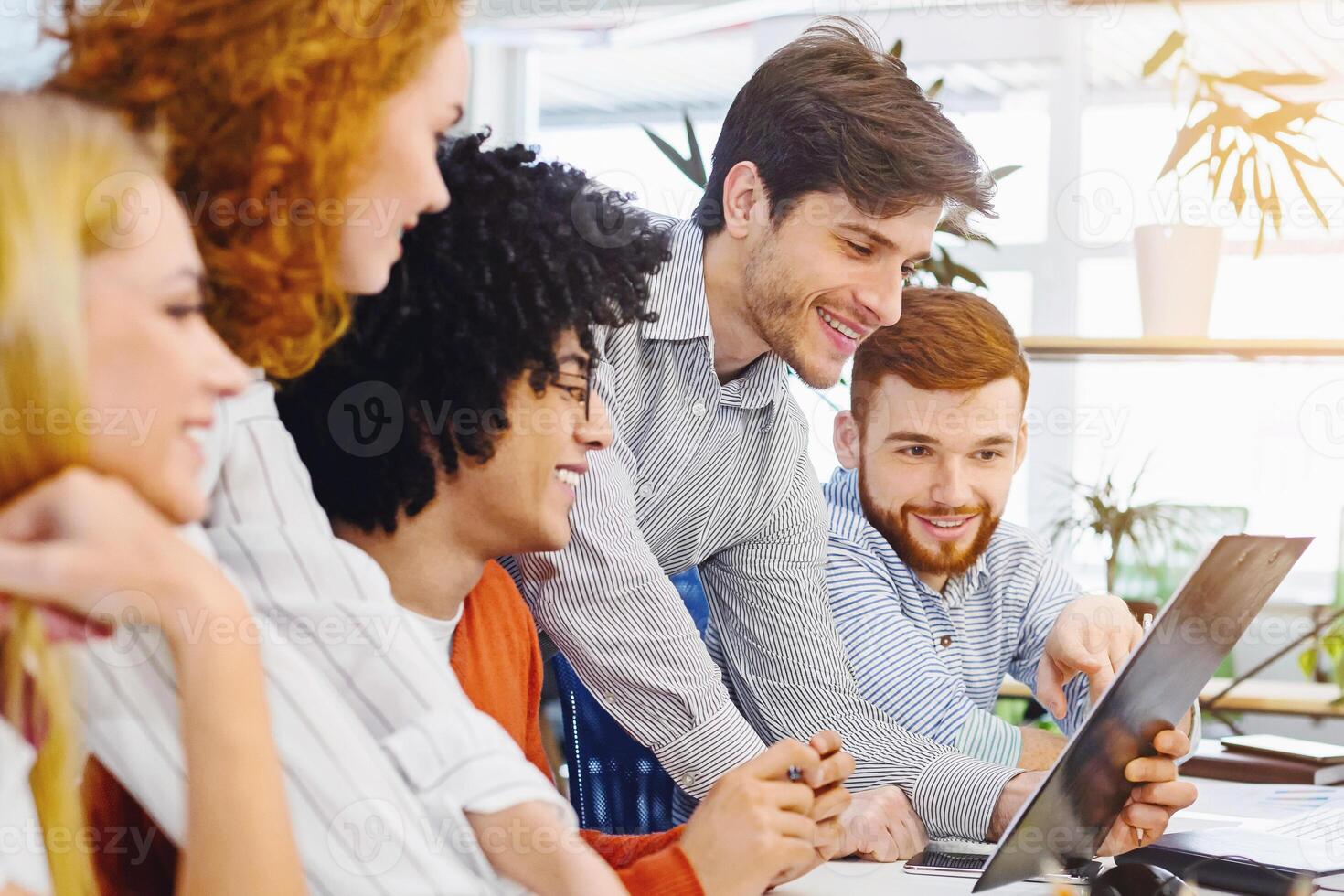 New business plan. Young cheerful people looking at clipboard at coworking workplace, free space photo