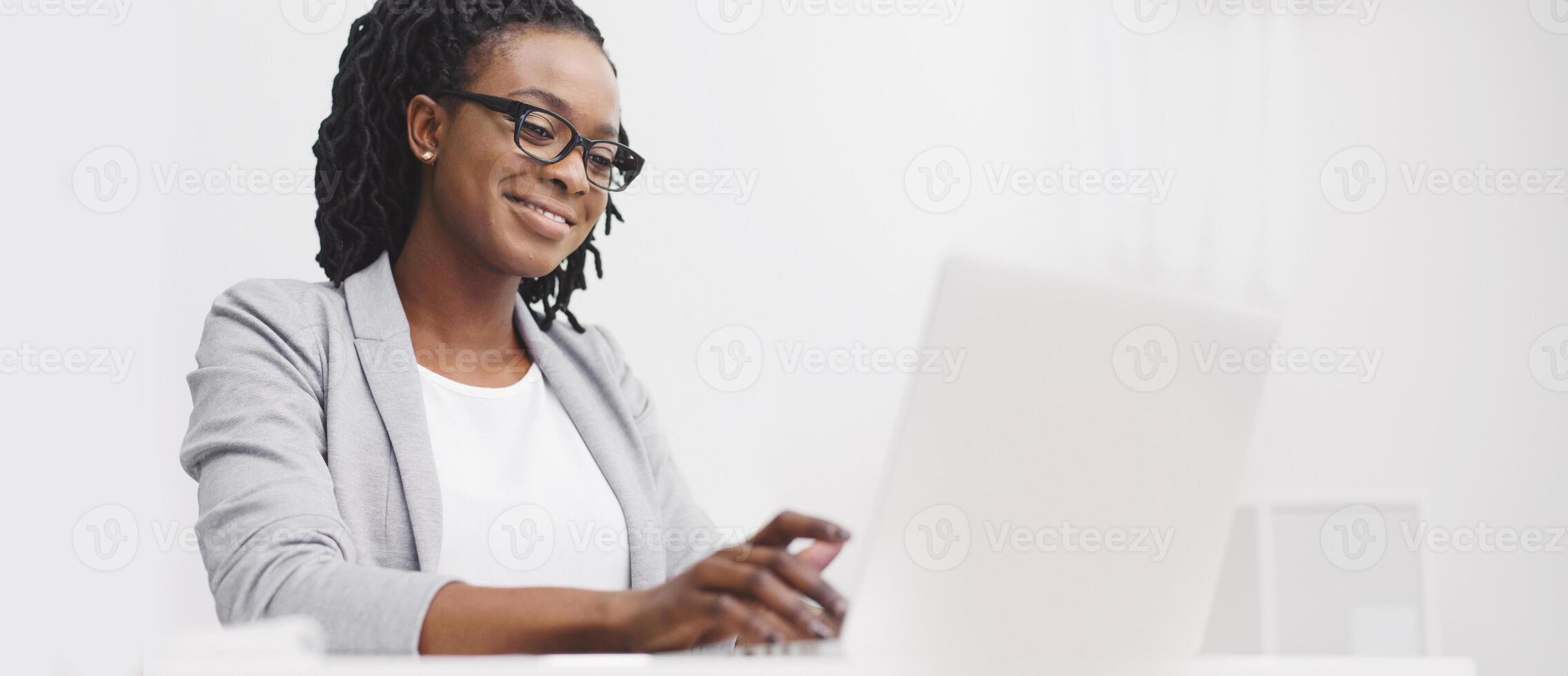 An office employee black lady is focused on her computer at her desk. The atmosphere is professional and modern, with a clean desk and bright space, highlighting concentration. photo
