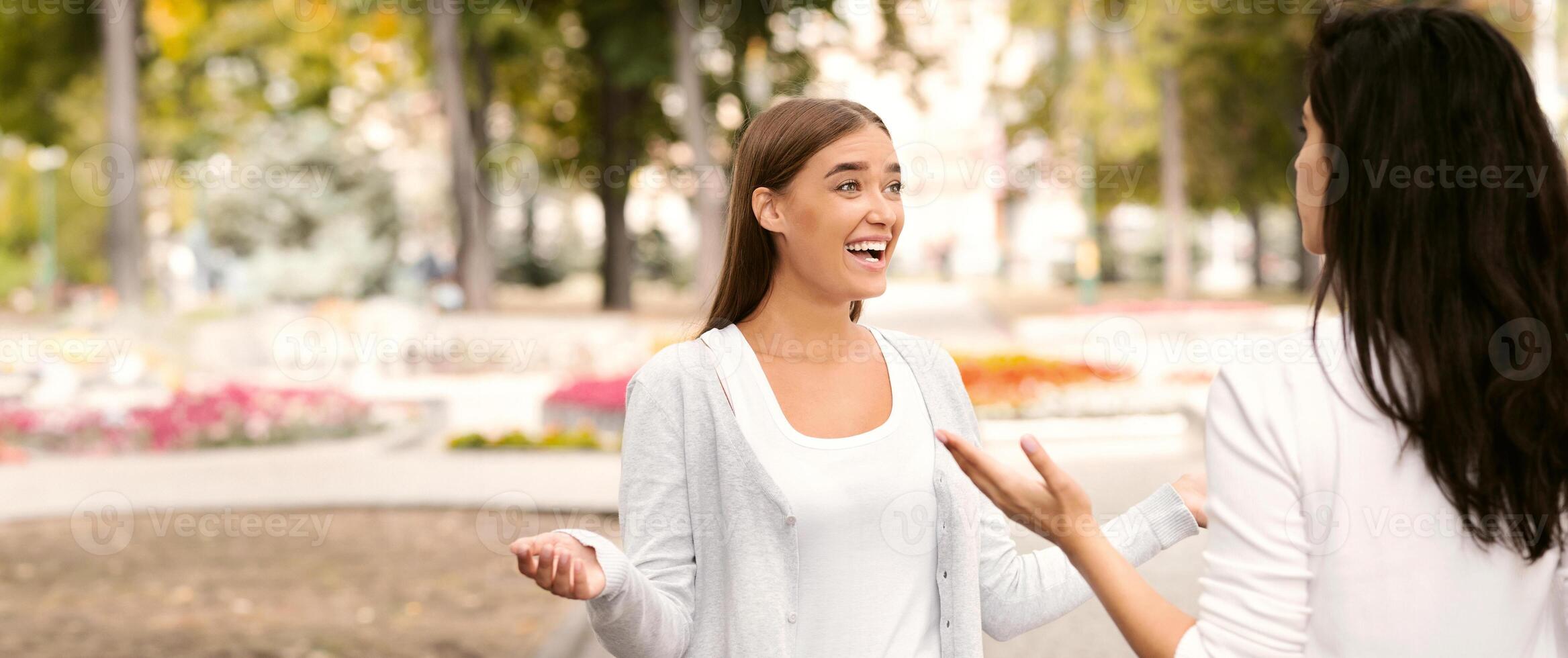 Happy Girl Meeting Female Friend Greeting And Talking Walking Outdoors In Park. Selective Focus photo