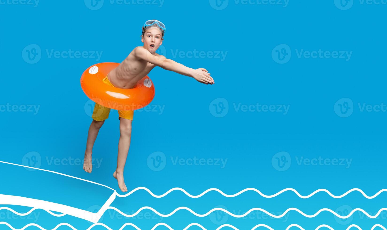 Teen boy in inflatable ring about to dive into swimming pool, blue studio background photo