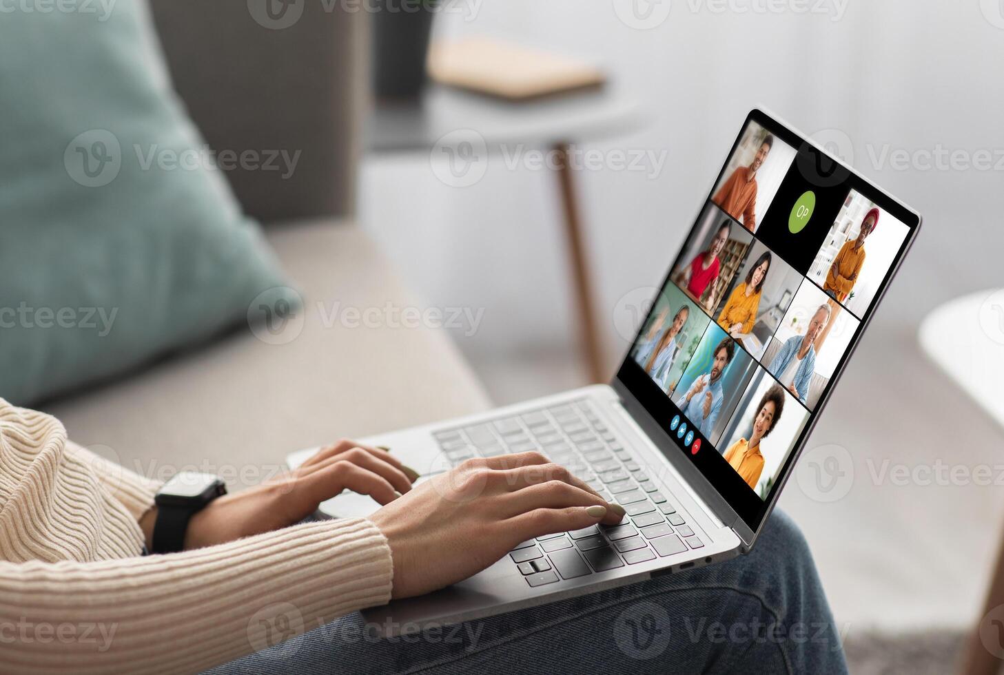 Woman participating in a conference meeting on her laptop. The screen of the laptop shows the faces of multiple people, each in a separate window photo