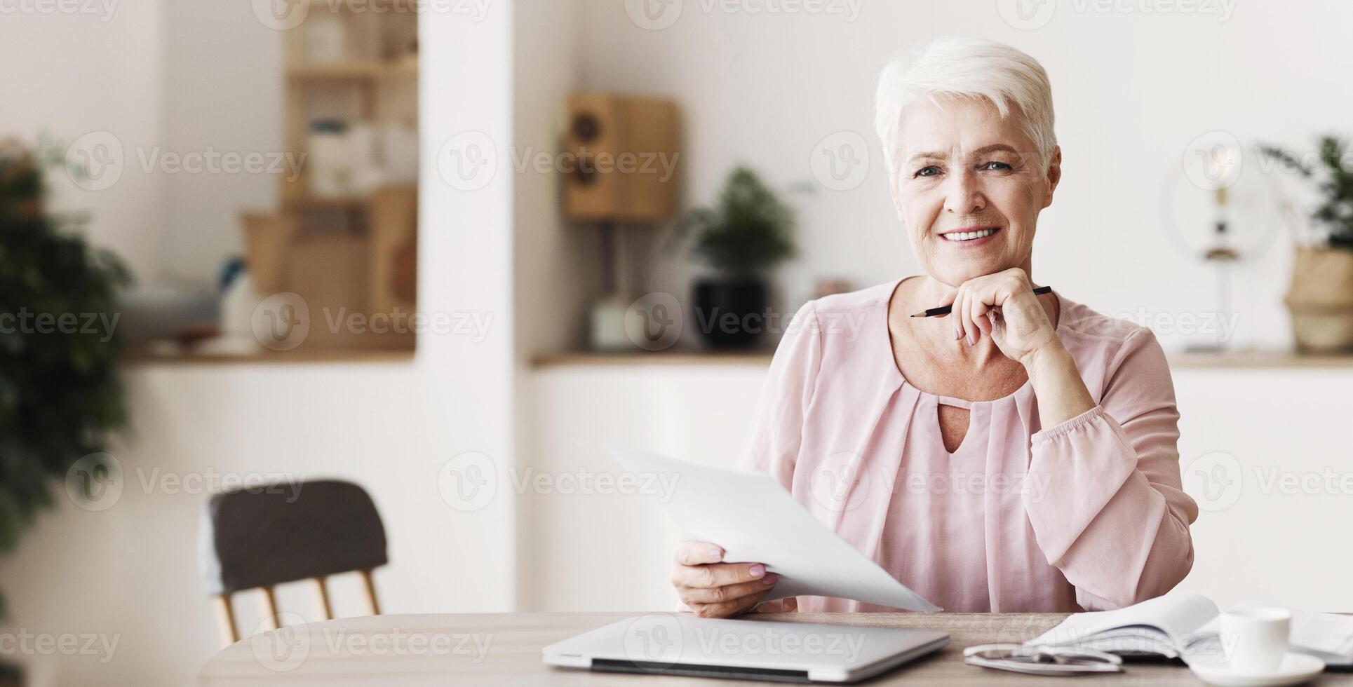 Happy senior business woman working with documents at home, editing text, copy space photo