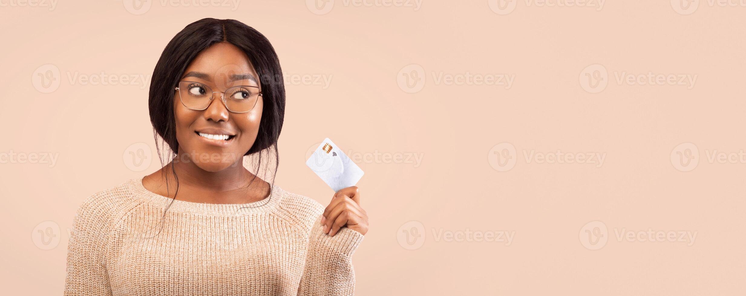 Smiling Black Woman Holding Credit Card Looking Aside Thinking About Something Standing Over Pink Background In Studio. Panorama photo